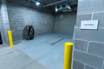 A car wash sign is on a wall in a concrete room.
